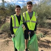 two boys in yellow vests cleaning up trash