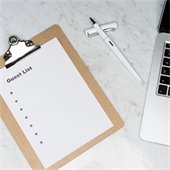 note pad with "guest list" written on top sitting next to a computer