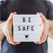 man holding a message board that says be safe