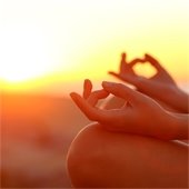 hands in yoga pose at sunset