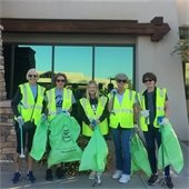 women in green vests with trash pickers and bags