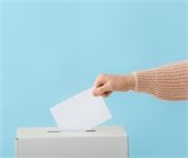 someone putting a ballot in a box